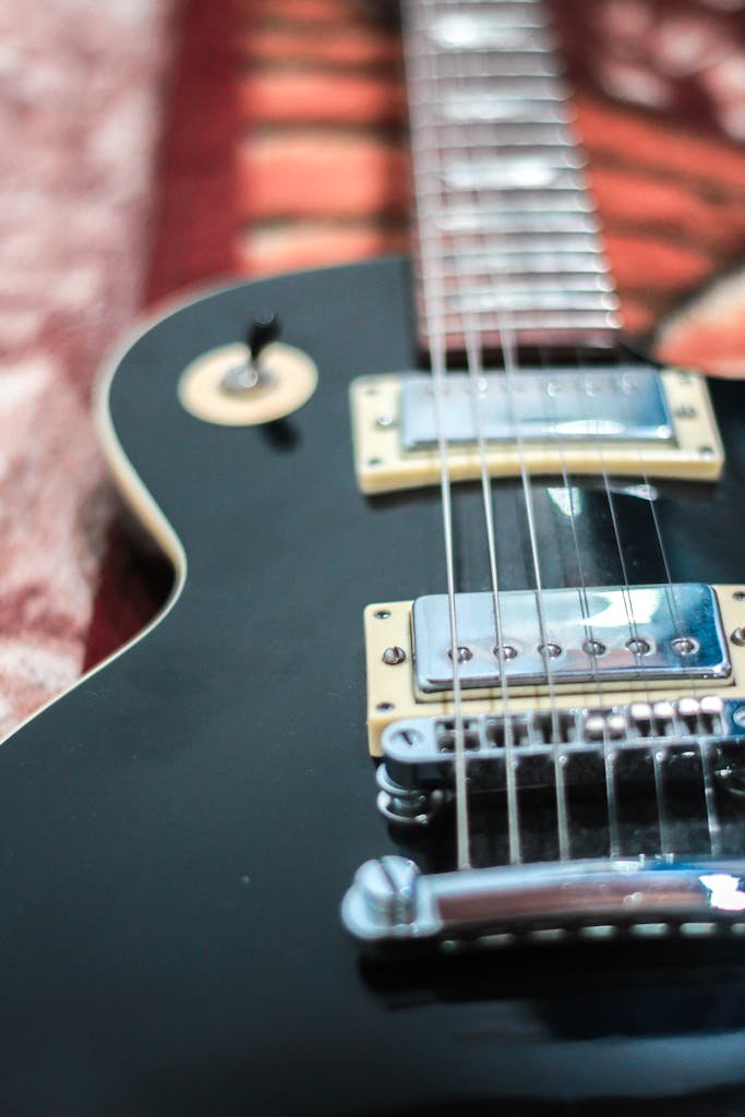 A detailed shot of a black electric guitar highlighting its strings and bridge.