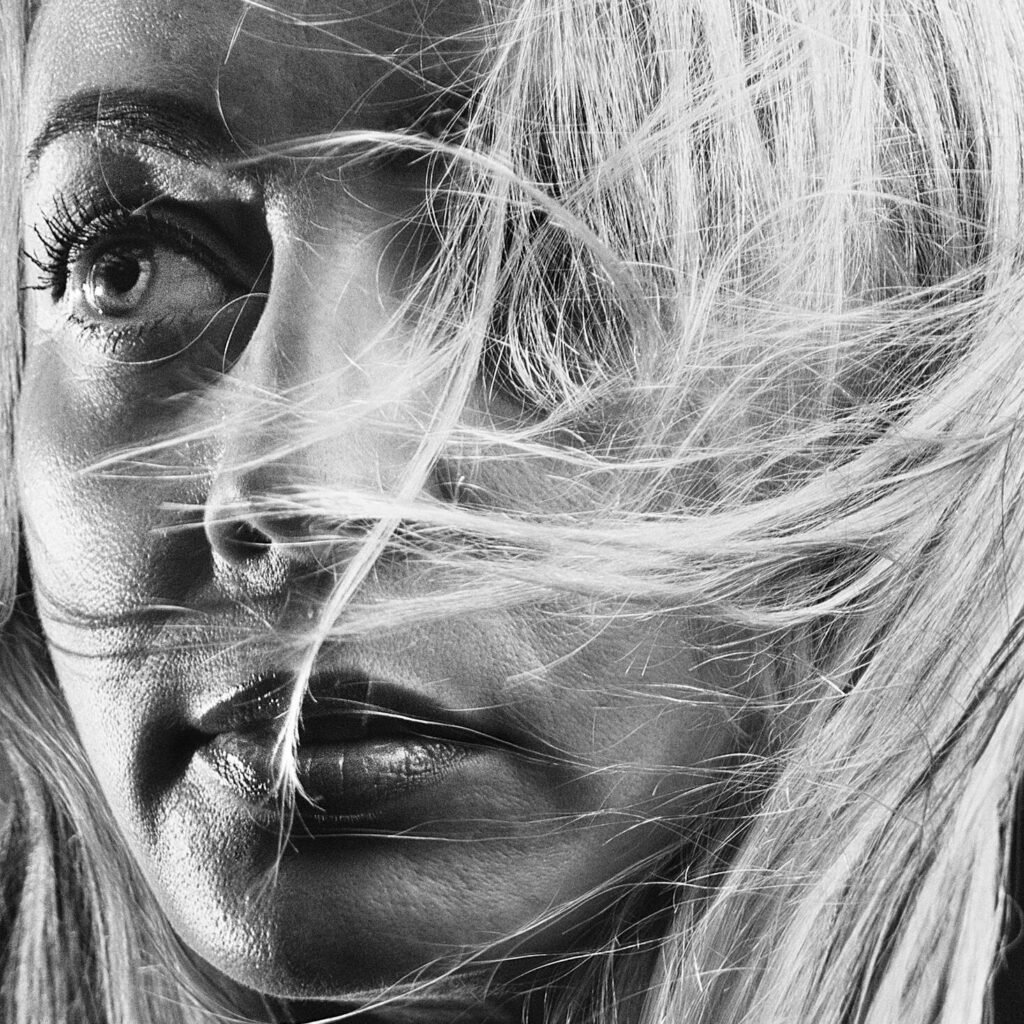 Captivating monochrome close-up of a woman with windswept blonde hair.