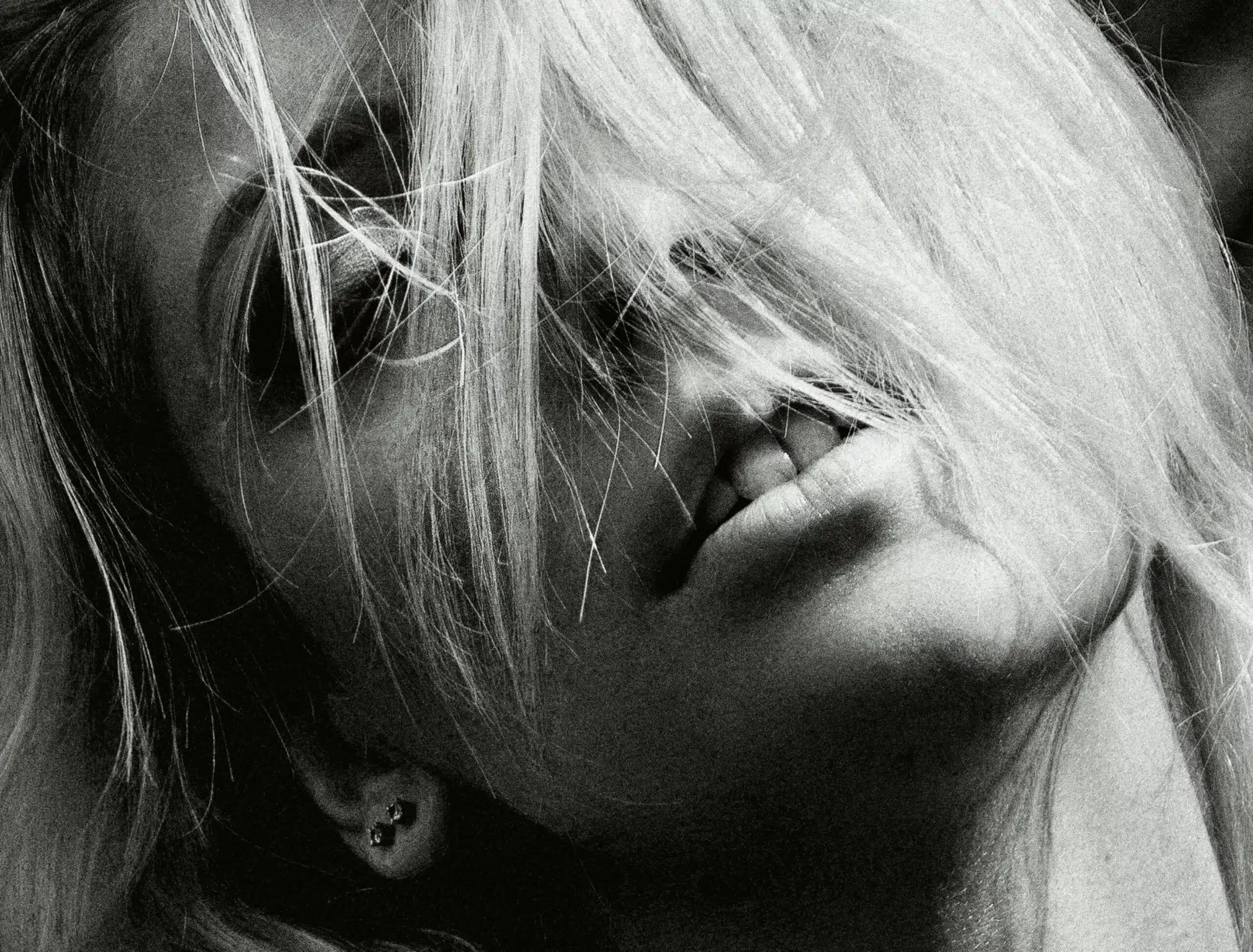 Polly 1 Dramatic black and white portrait of a woman with blonde hair and earrings, evoking a moody atmosphere.