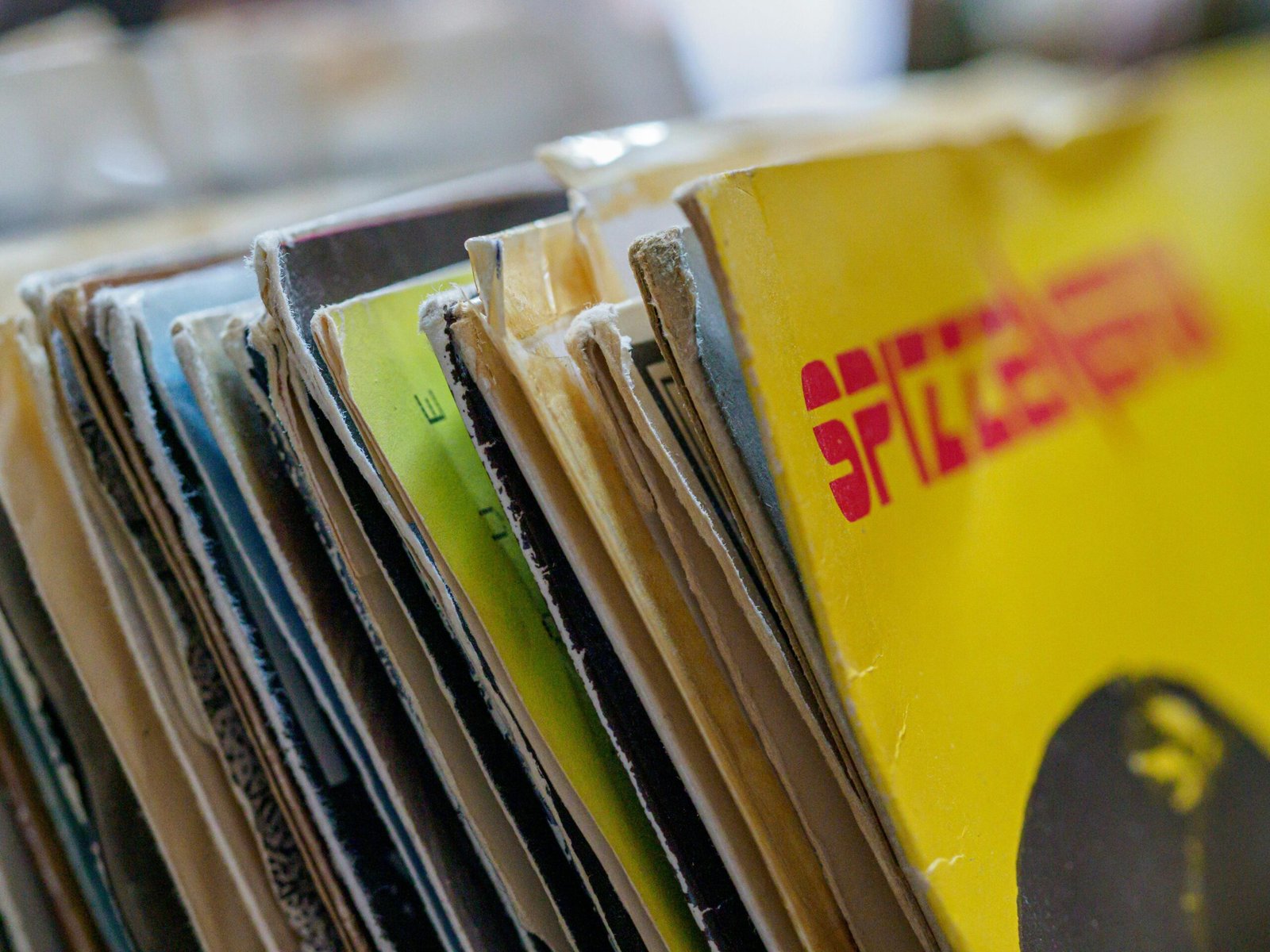 Colorful vintage vinyl record sleeves stacked together with a blurred background.