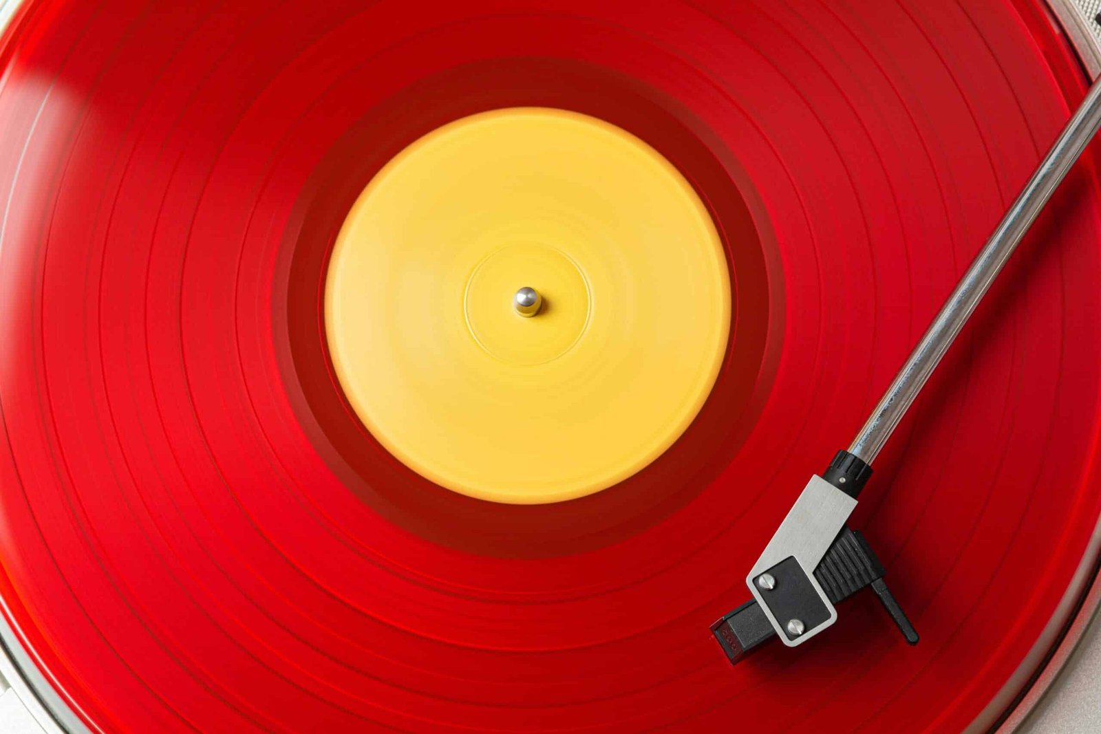 Close-up of a spinning red vinyl record on a turntable with a yellow center label.
