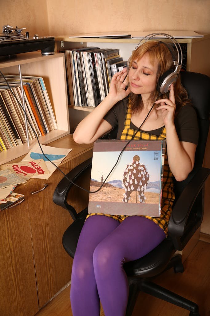 Woman relaxing with headphones and vinyl record, embracing music in a cozy room.