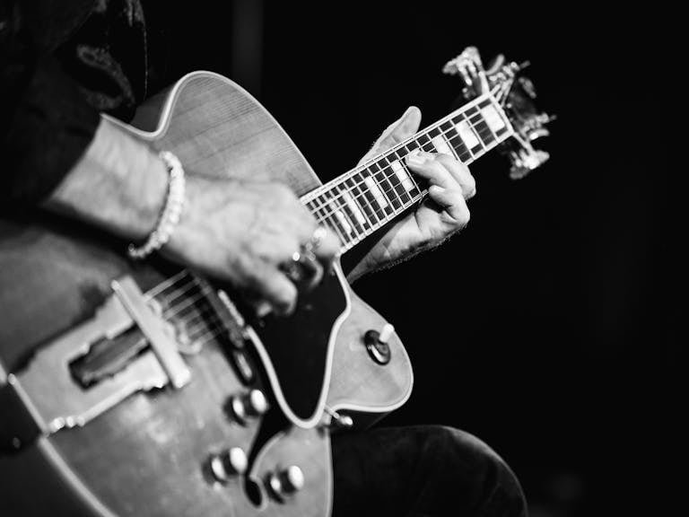 Black and white close-up of a guitarist playing an acoustic guitar with intense focus.