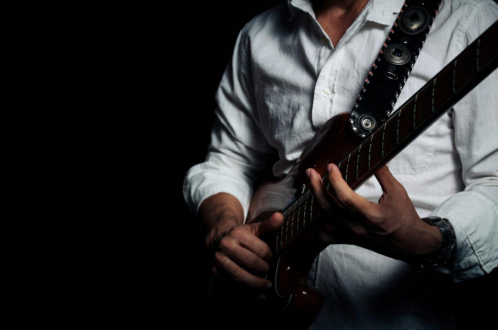 Da Charlie Christian a Jimi Hendrix: la Linea Diretta che Nessuno Racconta 1 Musician in a white shirt playing an electric guitar in a studio setting.