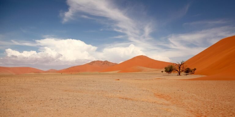 Breathtaking view of Namib Desert with towering red sand dunes and blue sky.