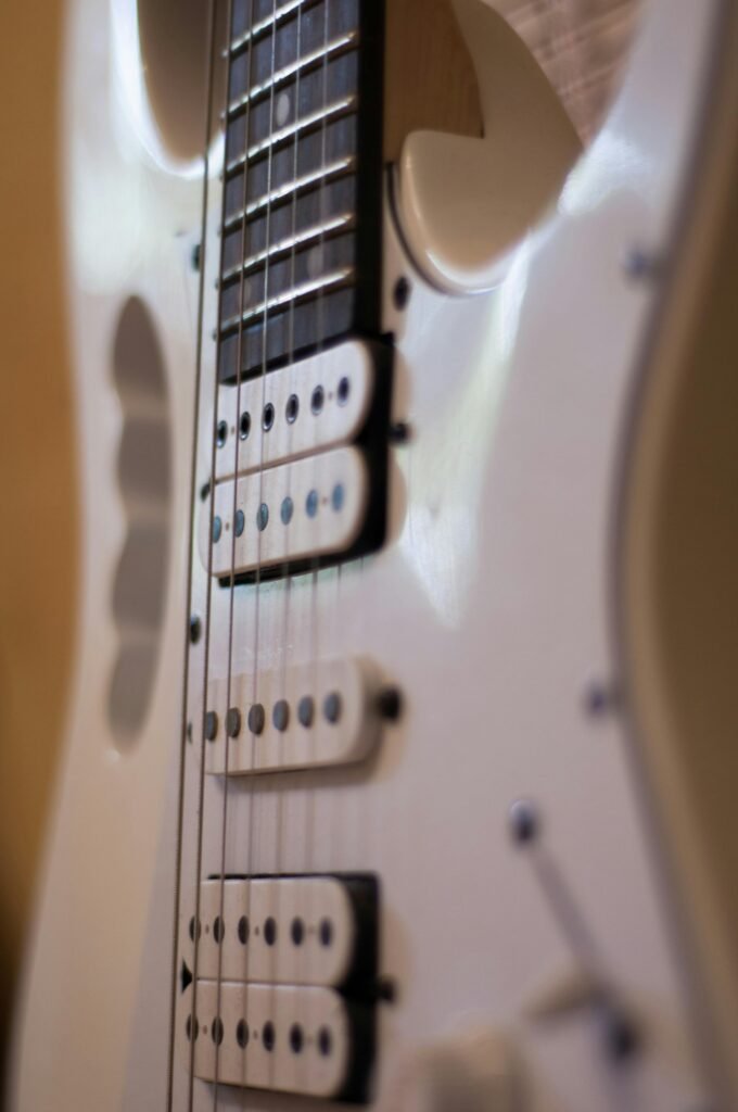 Detailed view of a white electric guitar highlighting strings and pickups.