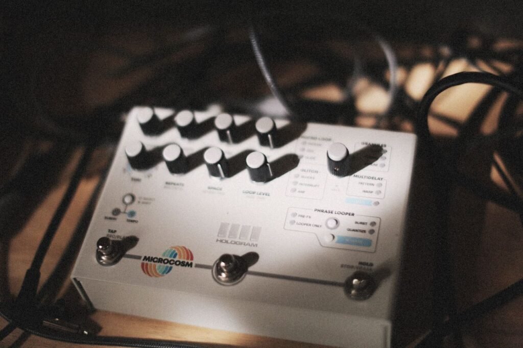 Il Guitar Synth, il Looper e il MIDI: quando la Chitarra diventa Orchestra 4 Close-up of audio effects pedal surrounded by cables in a dimly lit music studio, showcasing music technology.