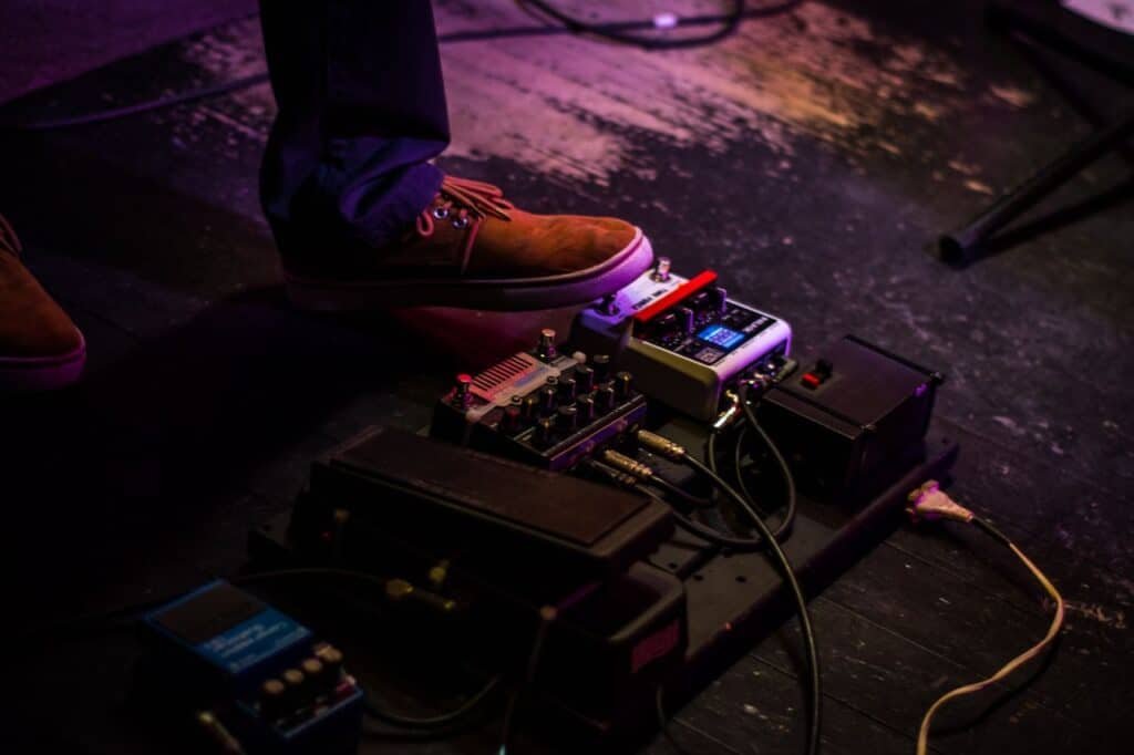Il Wah-Wah, la Distorsione e il Fuzz: i Tre Effetti che hanno Inventato il Rock 1 Close-up of a musician's foot operating a guitar pedal board during a live performance.